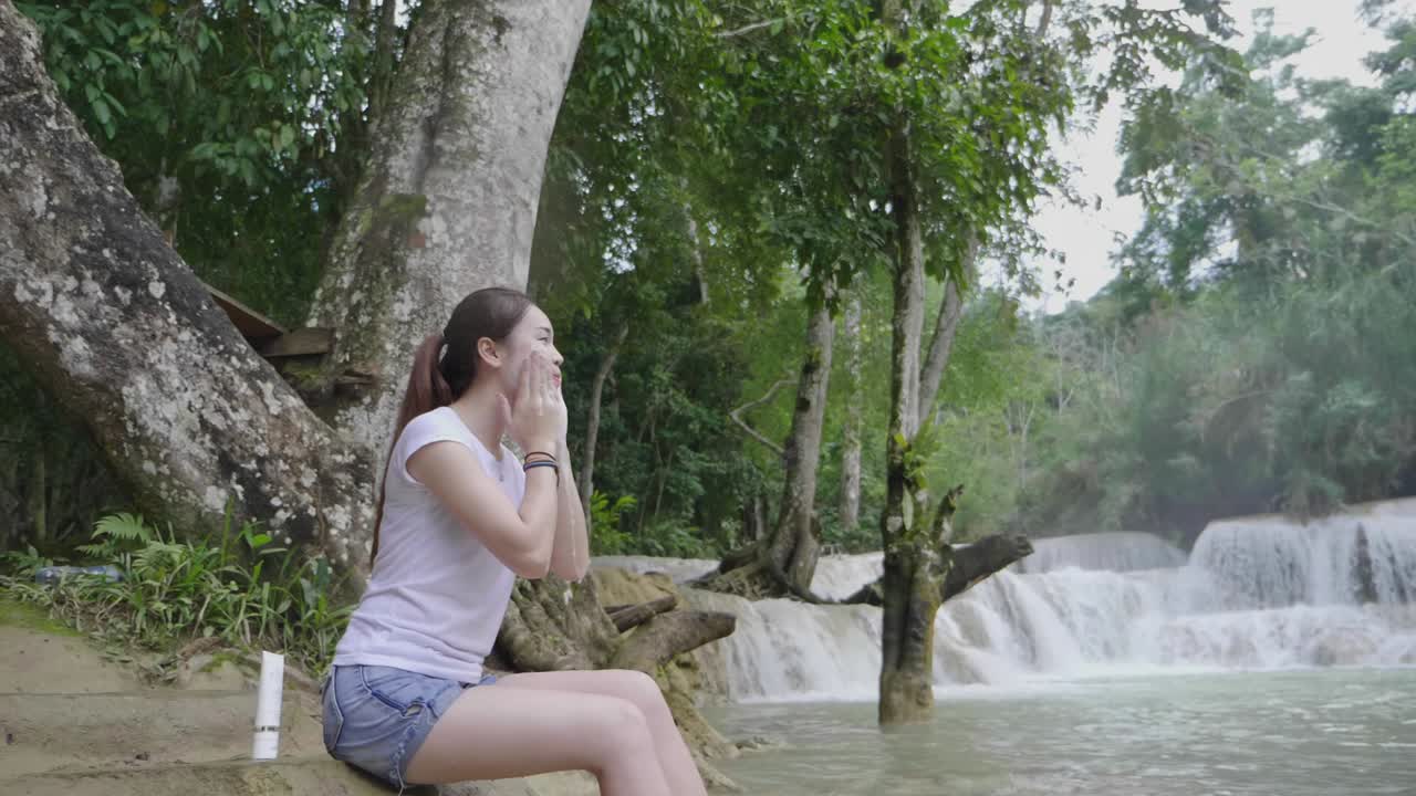 Woman Applying Face Cream at Waterfall
