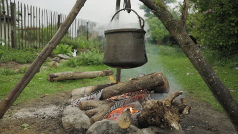 tetera de brujas humeando sobre el fuego, trípode sosteniendo una olla grande sobre llamas ardientes, plano general