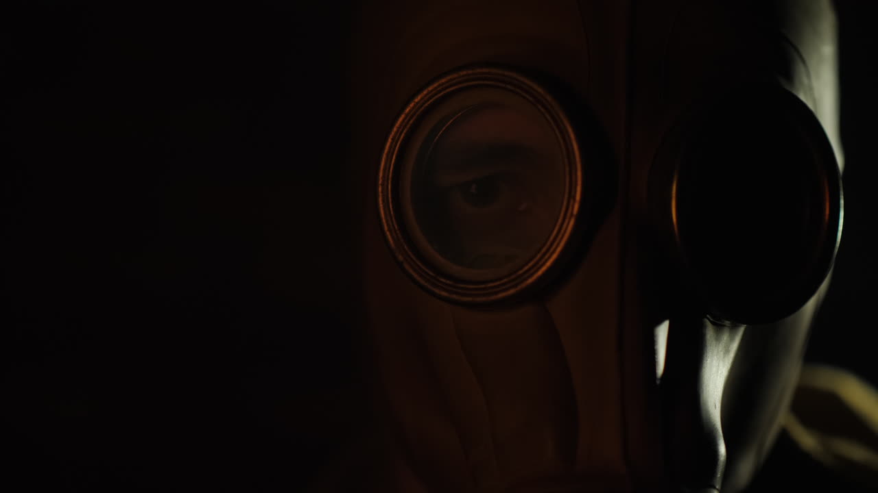 los destellos del fuego se reflejan en el ojo y la máscara de gas del hombre