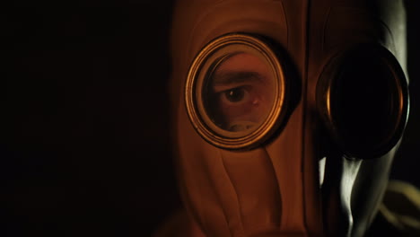 the gleams of the fire are reflected in the eye and gas mask of the man