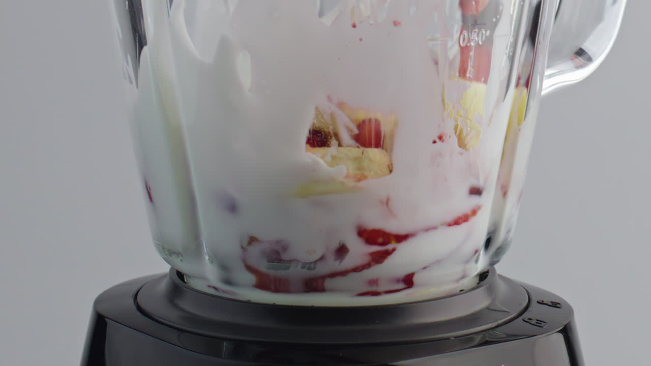 las frutas se añaden a la licuadora de leche de cerca. ingredientes naturales que caen líquido lácteo.