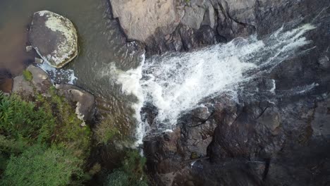 bella toma de una exuberante cascada filmada con un dron que se eleva hacia los árboles en un denso bosque