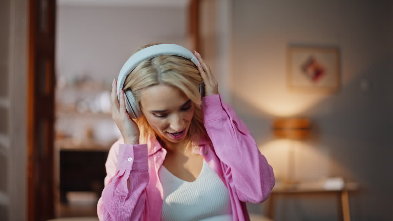 Excited woman dancing headphones in sunlight room closeup. Blonde listening song