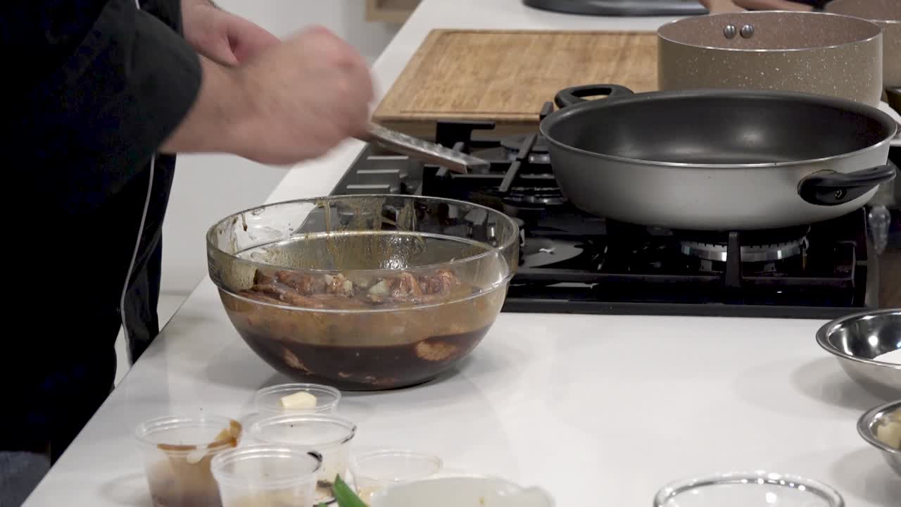 Chef prepares marinated chicken using an assortment of fresh ingredients. The process involves mixing flavors in a bowl, showcasing the art of cooking before heating