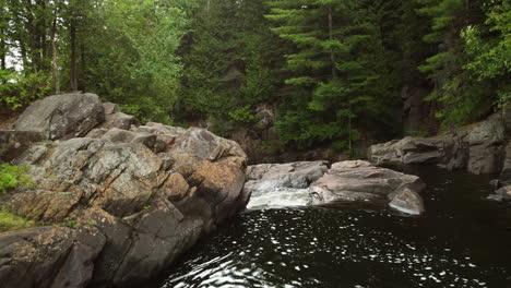 drone-shot-follows-river-through-forest-and-down-a-waterfall