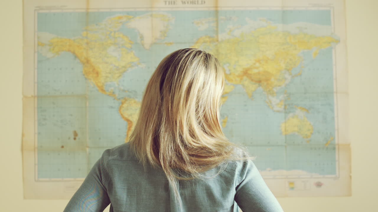joven turista mujer de viaje mira el fondo del mapa del mundo