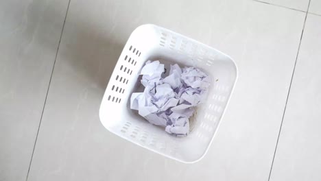 crumpled paper in a white trash can