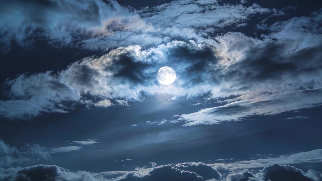 Awan berlapis yang melayang memperlihatkan bulan purnama di langit malam, menunjukkan tepian yang lebih terang dari cahaya bulan
