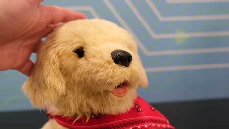 hand petting a cute golden retriever plush toy with a red bandana