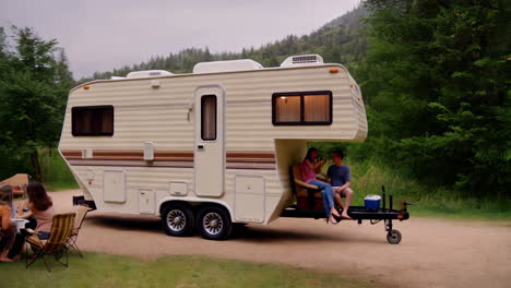 friends and family enjoying a leisurely time at a campsite with a large camper trailer