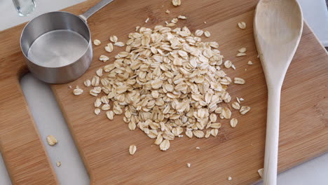 a pile of oats grain cereal being poured with kitchen utensils for a healthy oatmeal breakfast top down