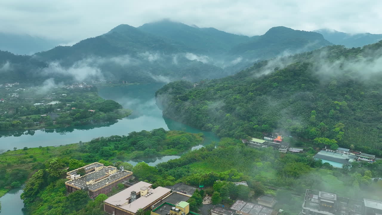 Sobrevoo aéreo de paisagem rural com rio e neblina perto de blocos de apartamentos em Taiwan
