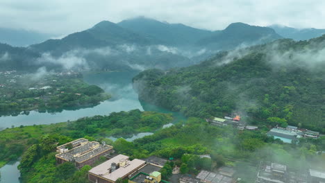 aerial flyover rural landscape with river and fog near block apartments in taiwan