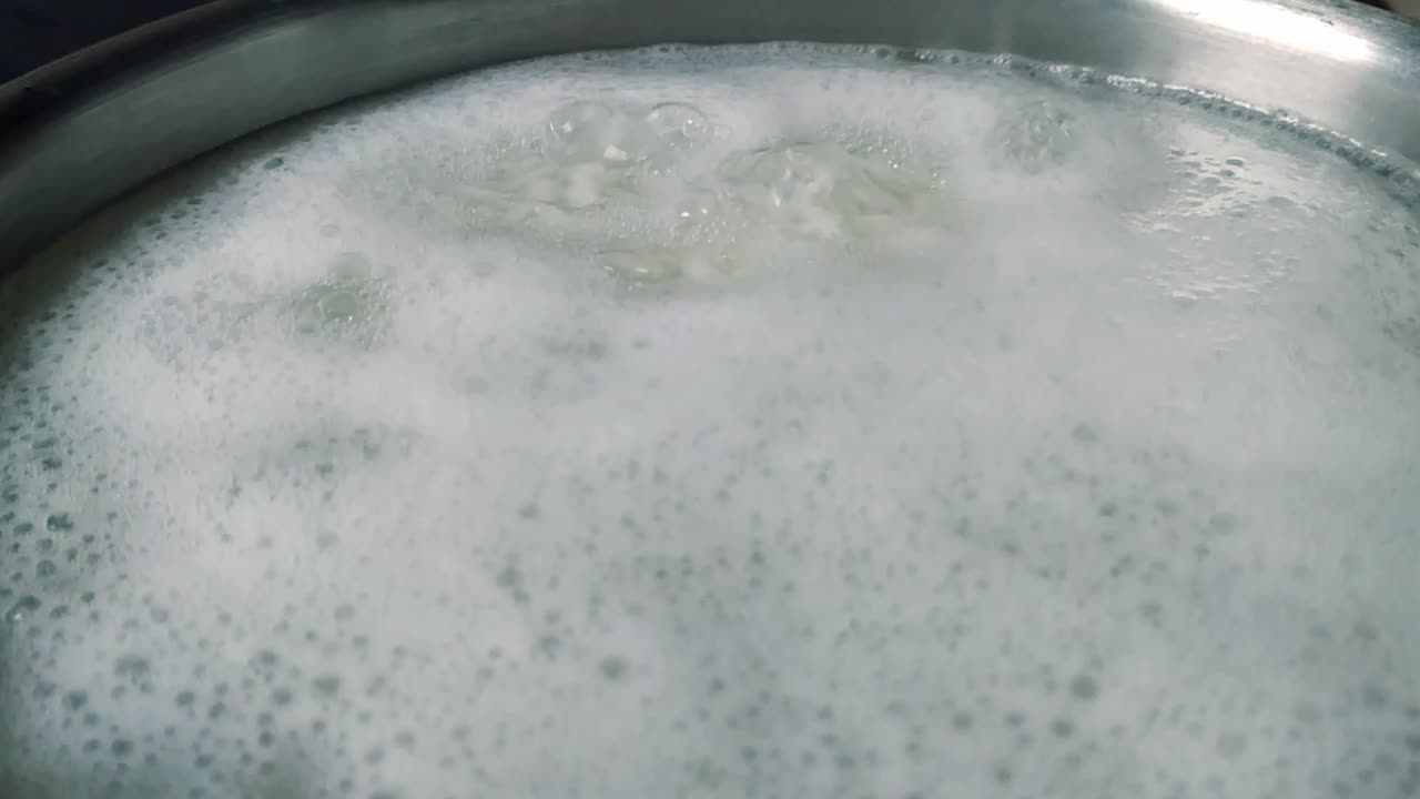 Homemade boiling white rice with bubbles in water in pot