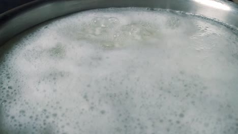 homemade boiling white rice with bubbles in water in pot