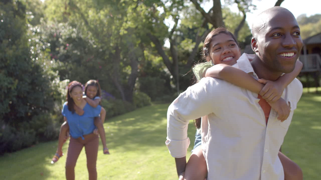Playing in park, parents giving piggyback rides to their children