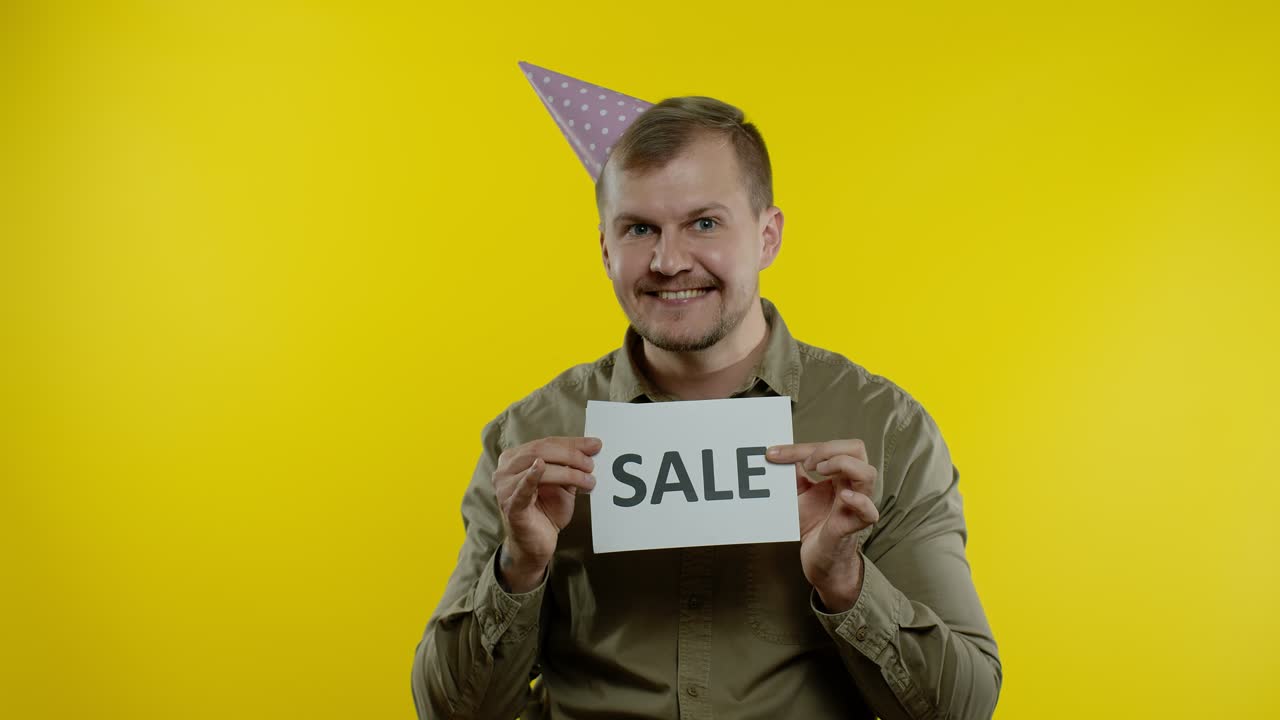 매력적인 남자가 판매 단어와 블랙 프라이데이 텍스트 문구를 보여줍니다. 휴가 할인, 저렴한 가격