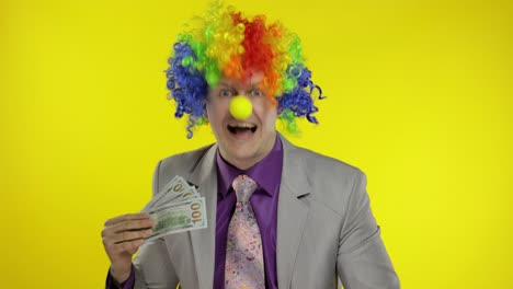 clown businessman entrepreneur boss in wig waves with money banknotes. halloween