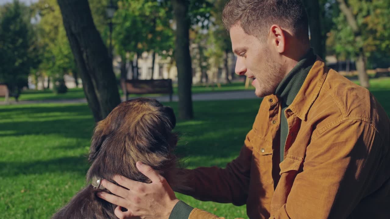 joven acariciando a su perro pastor alemán en el parque, mejores amigos, cámara lenta