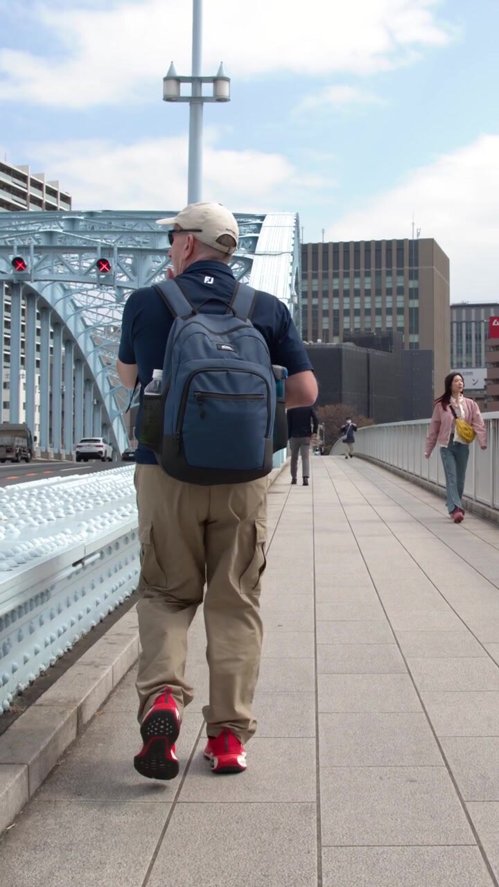 Un viaggiatore cammina lungo il marciapiede pedonale del ponte Eitai a Tokyo, Giappone.