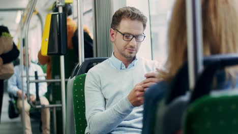 Hombre-Atractivo-Con-Anteojos-Desplazándose-Y-Escribiendo-En-El-Teléfono-Mientras-Se-Va-A-Casa-Después-Del-Trabajo-En-El-Tranvía-O-Al-Trabajo-Por-La-Mañana