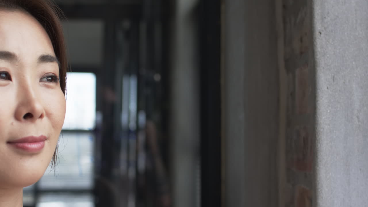 미묘한 메이크업을 가진 아시아 사업가 여성이 복사 공간이 있는 벽돌 벽에 기대어 있습니다.