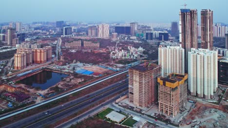 hyderabad under construction buildings beside nehru outer ring road with vehicles and tallest skyscraper at kokapet, financial district, telangana, india. day time, pan shot, drone shot, 4k.