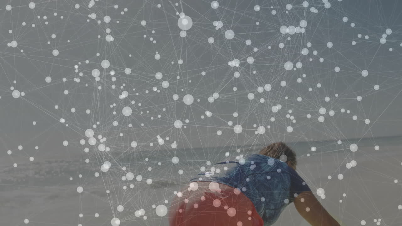 woman kneeling on red surfboard at shoreline, displaying digital network overlay for technology