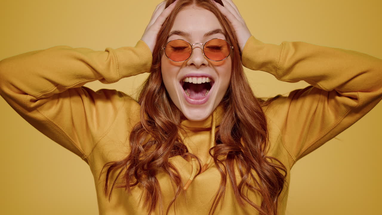 Emotional girl making hand gestures indoors. Woman clapping hands in studio
