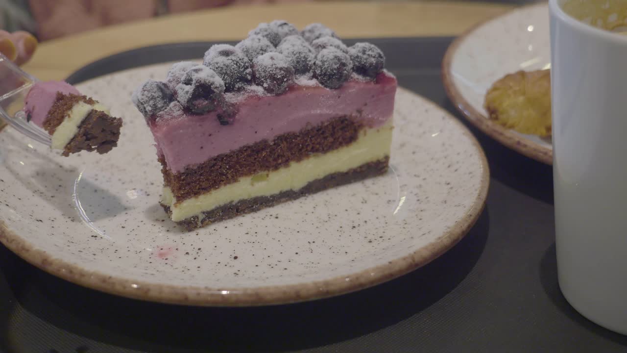 una rebanada de pastel de arándanos con una taza de café y una galleta en un plato