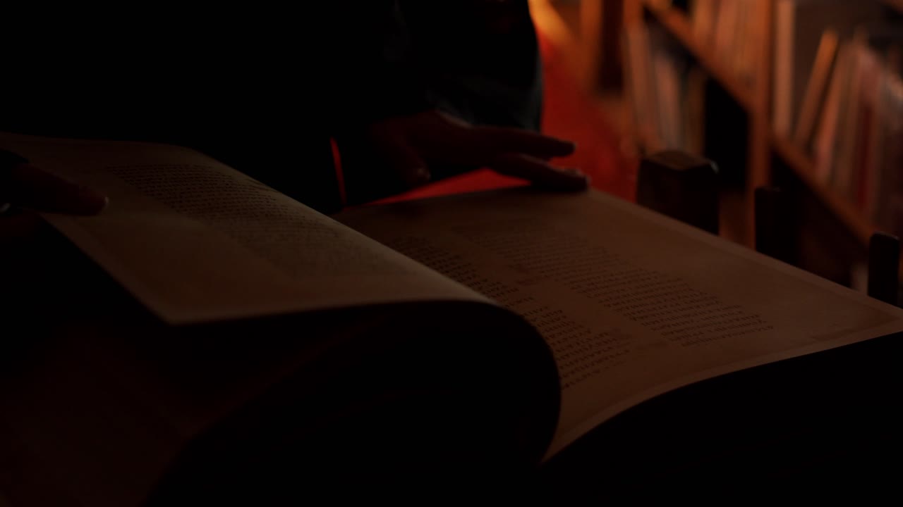 Persona che legge un vecchio libro in una biblioteca buia