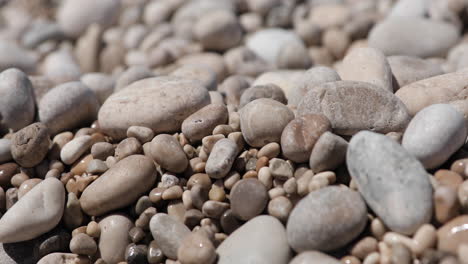 Beach-texture-with-pebbles-thrown-on-shore,-travel-and-vacation-concept