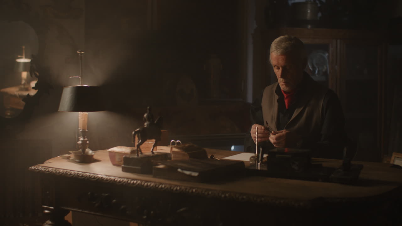 Older passionate man puts on the glasses in his office at night