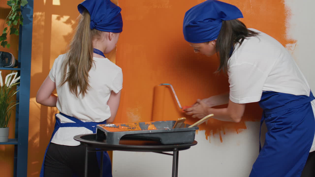 Mother and daughter painting a wall orange