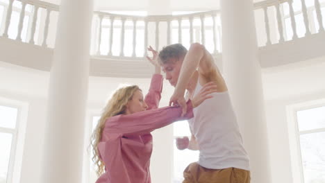 vista inferior de un par de bailarines contemporáneos bailando en medio del estudio