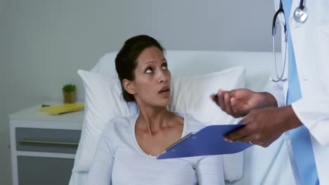 Front-view-of-African-american-female-patient-talking-with-male-doctor-in-the-ward-at-hospital