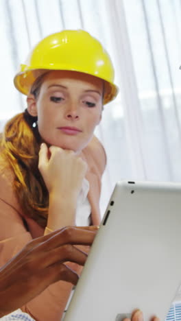 mujer de negocios y compañeros de trabajo discutiendo en una tableta digital