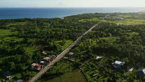 picturesque aerial forward of lush countryside road amid tropical greenery and village towns at timbaan, san andres, catanduanes, philippines.