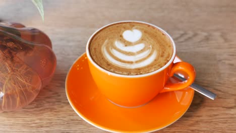 orange cup of cappuccino with latte art