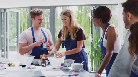 y estudiantes adultas midiendo ingredientes masculinos en la clase de cocina en la cocina