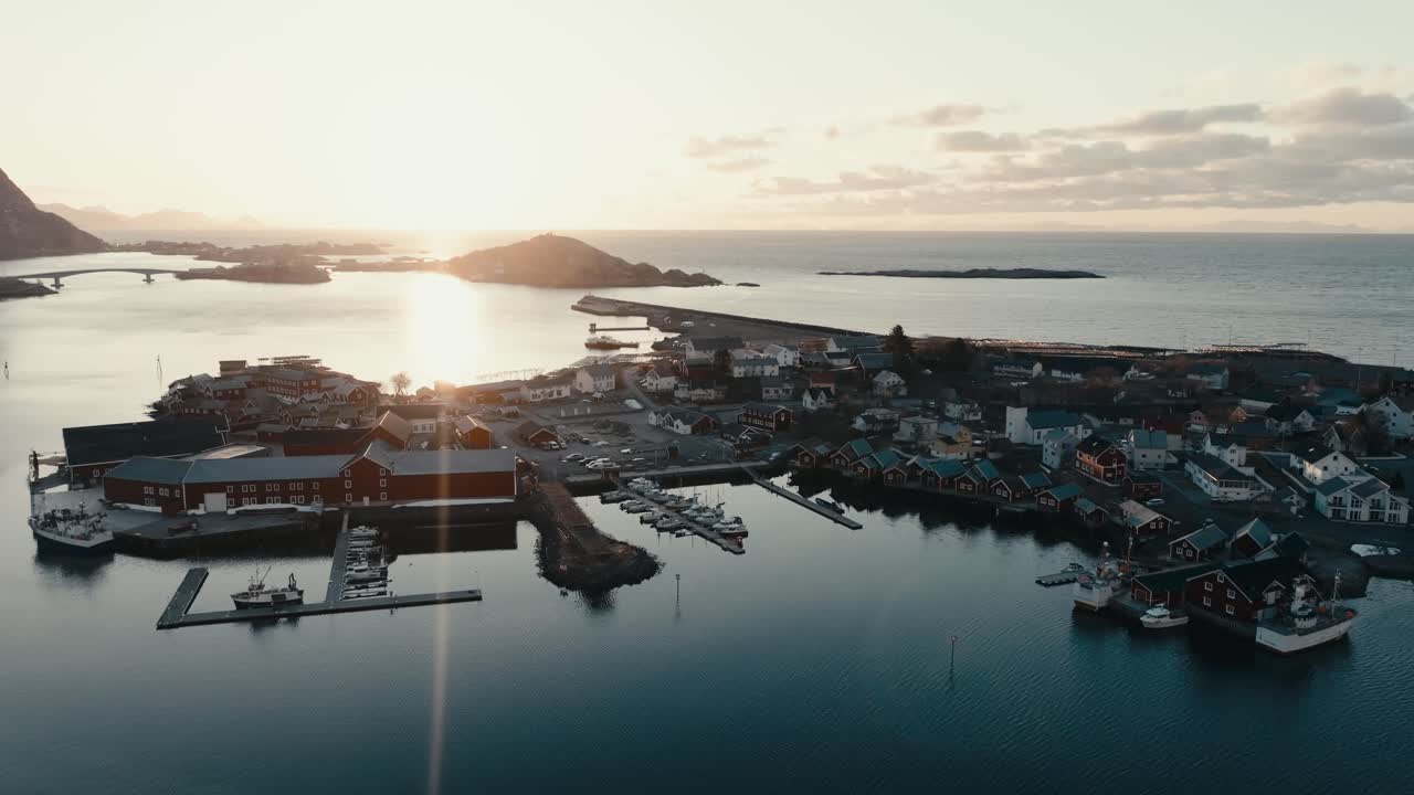 Dazzling Sun Shining Over The Tranquil Water Of Sea By Reine Village At Sunrise In Norway. - aerial shot
