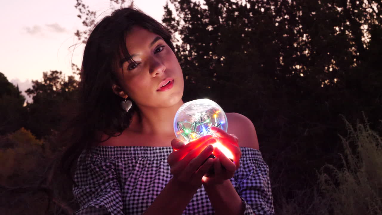 una hermosa y misteriosa mujer hechicera vagando en un paisaje de fantasía con un orbe espiritual mágico brillando en luz iluminada