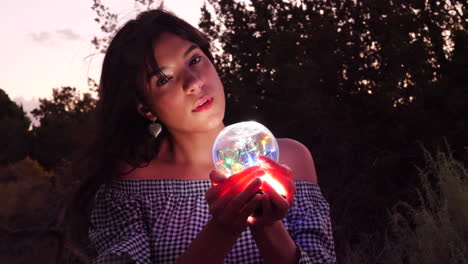 A beautiful and mysterious woman sorceress wandering in a fantasy landscape with a magic spiritual orb glowing in illuminated light