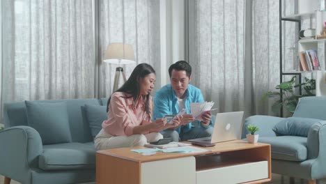 asian couple with a laptop holding credit card and smartphone having headache due to unable pay money
