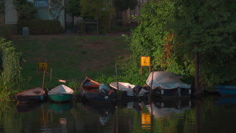 row of small boats on a quiet, pretty day floating on a dutch canal