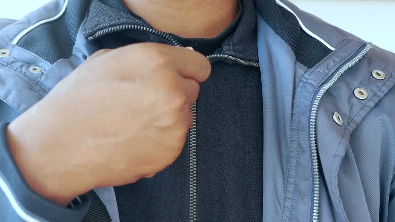 hombre cerrando su chaqueta gris
