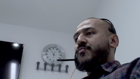 asian man wearing microphone headset working night shift talking with customer as one of online technical support team