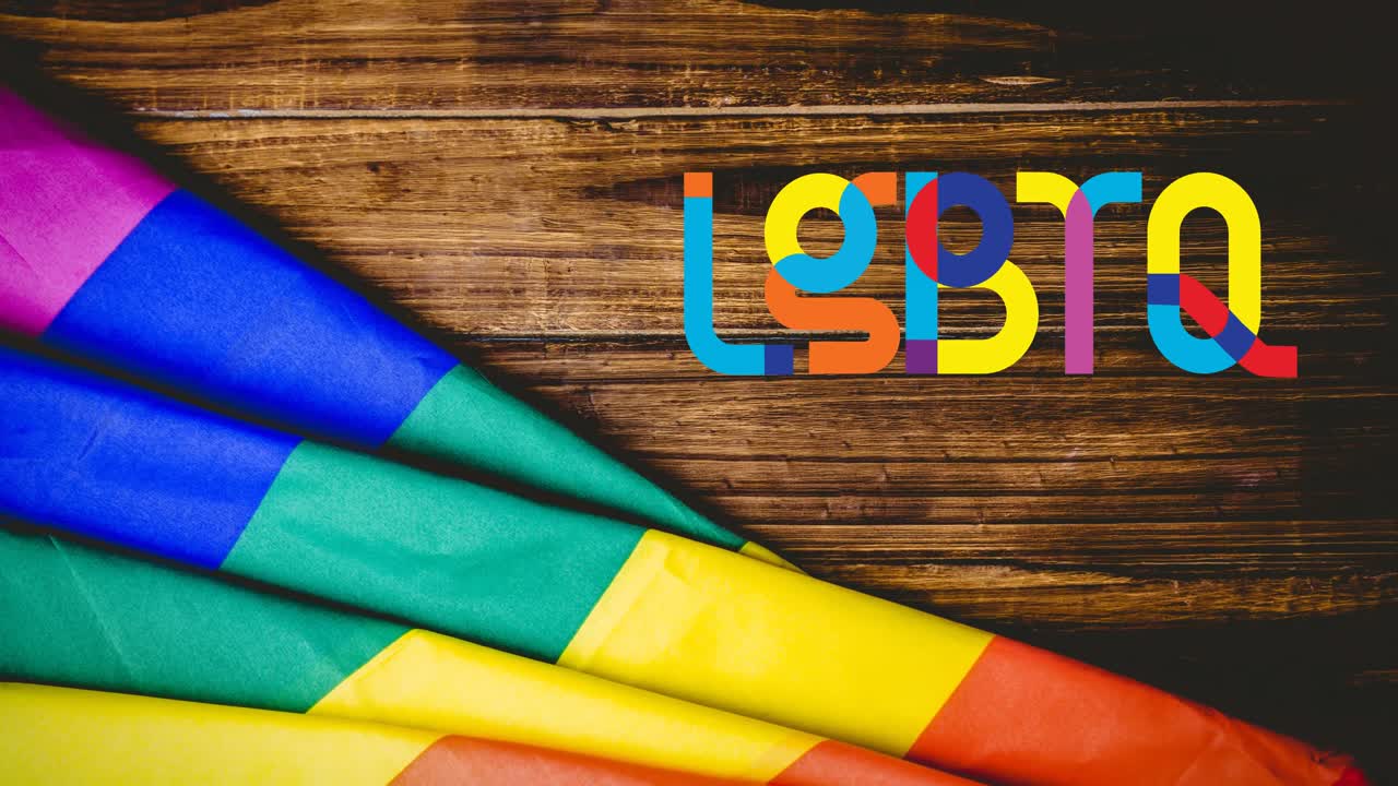 Animation of lqbtq text and rainbow flag over wood table background