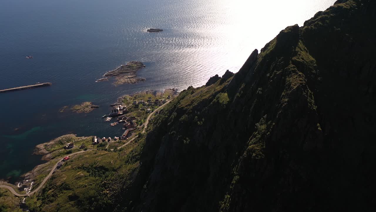 paisaje áspero de lofoten con montañas cayendo al mar y un pueblo junto a la costa