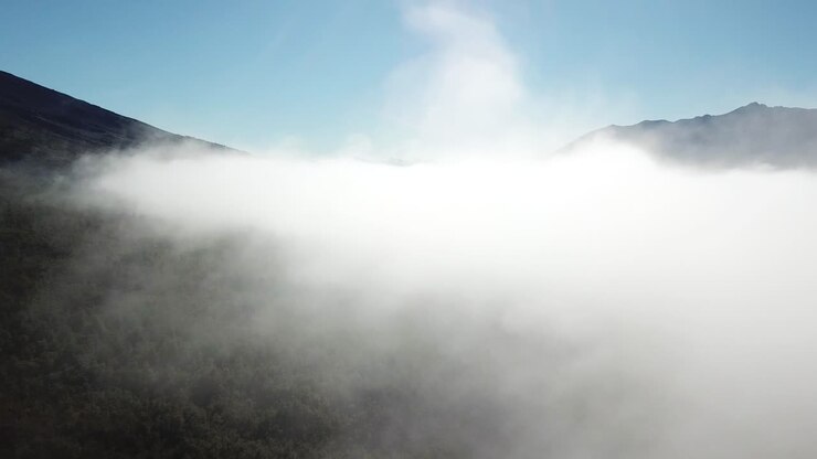 I skyerne over vulkanbjerge og jungle i Sydamerika. Luftfoto
